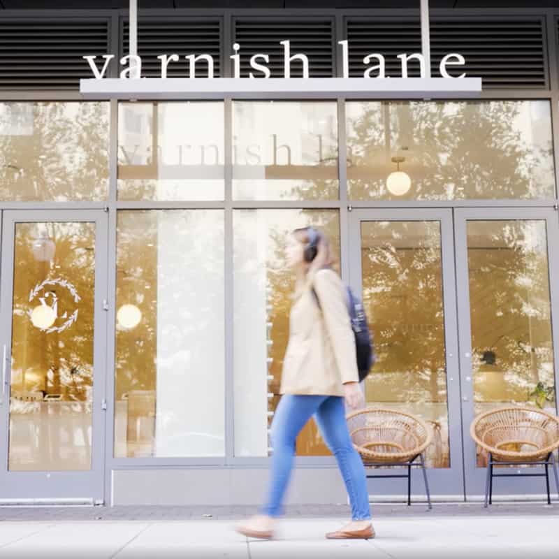 A woman walks past a store called Varnish Lane