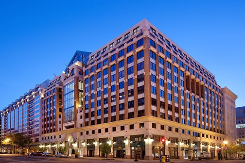 Tan brick office and retail building on busy city street at night